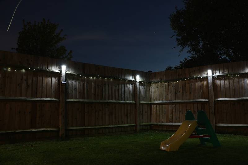 fence illuminated by solar lights at night